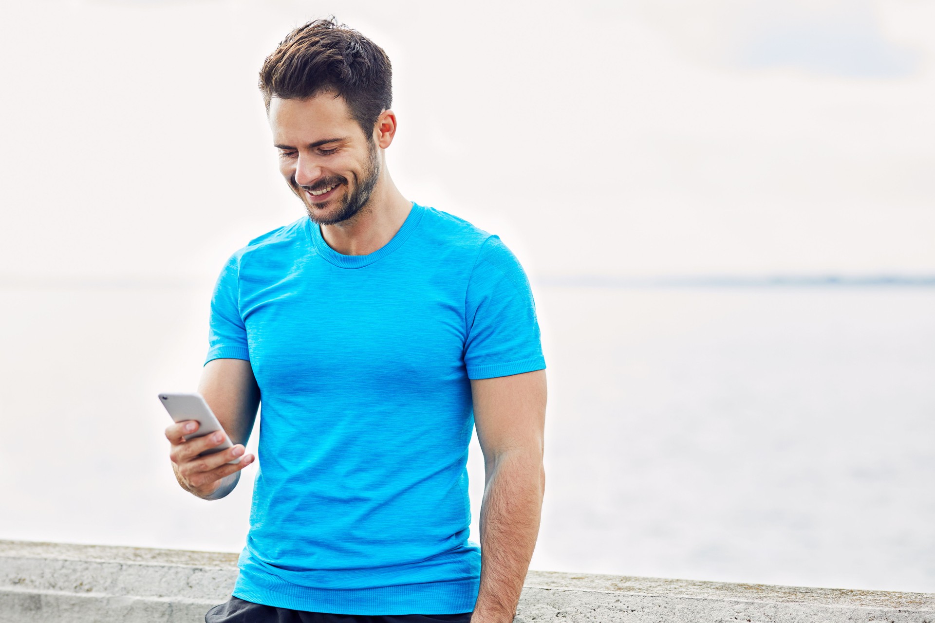Happy man checking his phone during outdoors workout